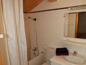 Un baño con ducha, inodoro, lavamanos y un espejo sobre el lavamanos.