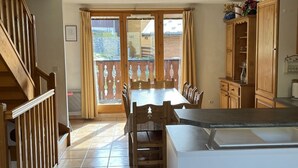 Una cucina con tavolo, sedie, una scala e un armadietto.