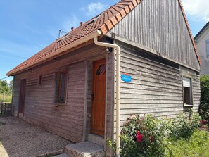 Ein hölzernes Gebäude mit einem Ziegeldach, einer Holztür und einem Schild, das auf einen Betrieb hinweist.