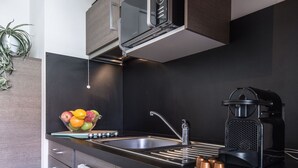 Una cocina moderna con encimera negra, pileta de acero inoxidable y cafetera.