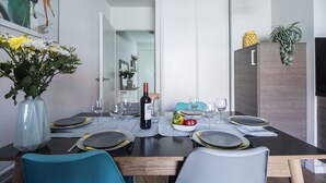 Mesa de comedor preparada para cuatro personas, con una botella de vino, platos y cubiertos.