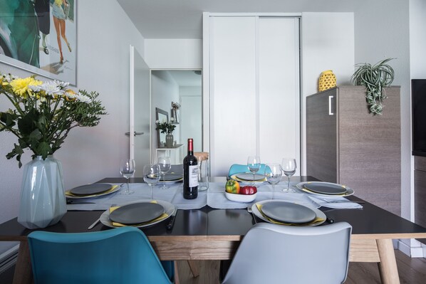 A dining table set for four with a bottle of wine, plates, and cutlery.