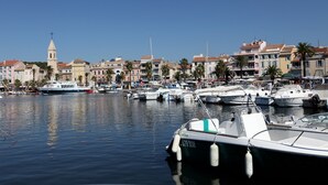A marina with boats docked, a prominent tower, and buildings with red-tiled roofs.