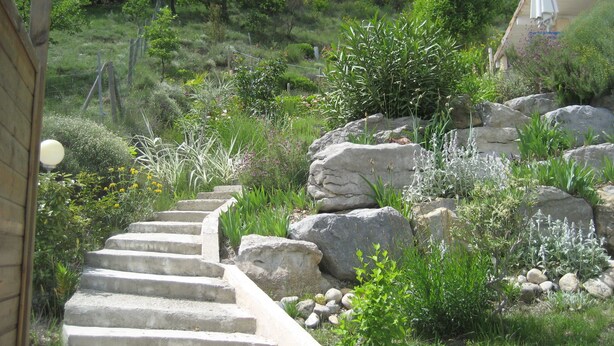 A stone staircase leading up a grassy slope with large rocks and various plants. - Private pool for 4 people, air conditioning, landscaped garden and superb view (Lussas)
