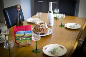 A wooden dining table with a bundt cake, wine bottles, and wine glasses. - Deer cottage, comfort of 130 m2 with view on the park a hinds (Sommerau)