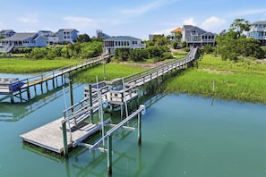 A waterfront property with a dock extending into a calm body of water, surrounded by lush greenery and residential buildings.