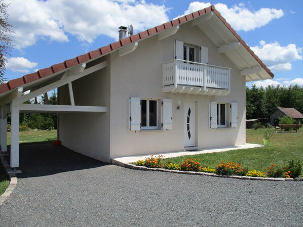 Una casa de dos pisos con balcón, garaje y entrada para vehículos.
