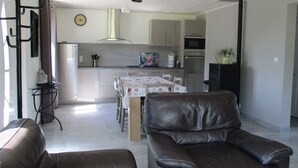 Una cucina moderna con zona pranzo, un soggiorno con arredamento in pelle e un orologio a muro.