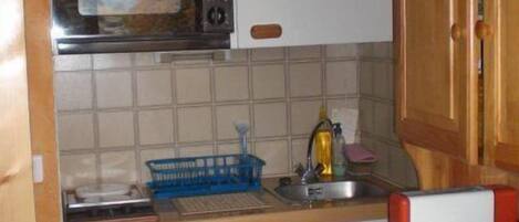 Une cuisine de taille réduite équipée d’un four à micro-ondes, d’un petit évier et d’un réfrigérateur compact.