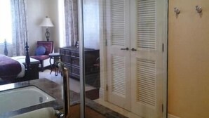 Une chambre d’hôtel avec un grand lit, une salle de bain avec baignoire, un bureau et une chaise.