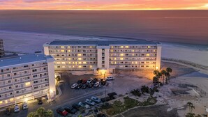 A hotel with multiple floors and a parking area in front, overlooking a beach. - Beach Front View/access. Updated finishes and open floor plan.   (Fort Myers Beach)