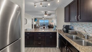 A modern kitchen with stainless steel appliances, dark cabinetry, granite countertops, and a view to the outside. - Beach Front View/access. Updated finishes and open floor plan.   (Fort Myers Beach)