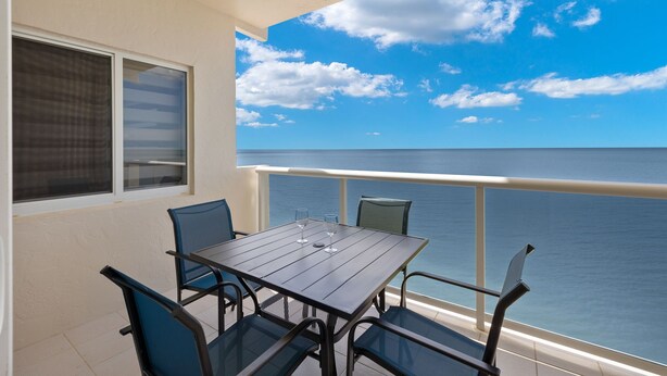 A balcony with a table and chairs, overlooking a body of water. - Beach Front View/access. Updated finishes and open floor plan.   (Fort Myers Beach)