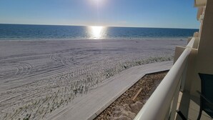 A beach view from a balcony with a clear sky and the sun reflecting on the water. - Beach Front View/access. Updated finishes and open floor plan.   (Fort Myers Beach)