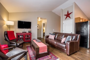 Un salon avec un canapé en cuir, un meuble rouge, une télévision et une décoration en forme d’étoile rouge sur le mur.