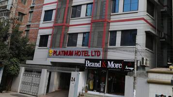 A multi-story hotel with a prominent 'Platinum Hotel Ltd' sign, a 'Brand & More' store on the ground floor, and a 'No Parking' sign in front.