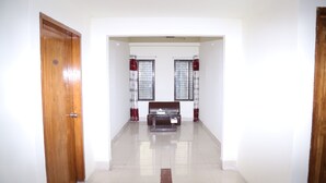 A hallway with a wooden door, a bench, and two windows with curtains. - Platinum Hotel Ltd (Dhaka)