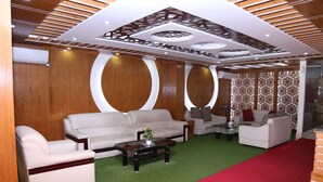A modern living room with a red carpet, two sofas, a coffee table, and decorative wall panels. - Platinum Hotel Ltd (Dhaka)