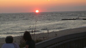 Tramonto sull'oceano con una spiaggia in primo piano.