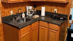 A kitchen with wooden cabinets, a granite countertop, a coffee maker, a kettle, and a stove. - Jewell between Fall Creek Falls, Burgess Falls and Rock Island State Parks (Sparta)