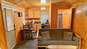 A cozy cabin interior with a wooden dining area, a sofa, and a small round table. - Jewell between Fall Creek Falls, Burgess Falls and Rock Island State Parks (Sparta)