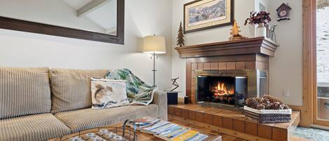 Una sala de estar acogedora con chimenea, un sofá y una mesa de centro con revistas.