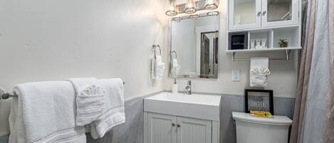Un baño con tocador blanco, un espejo grande y un inodoro.