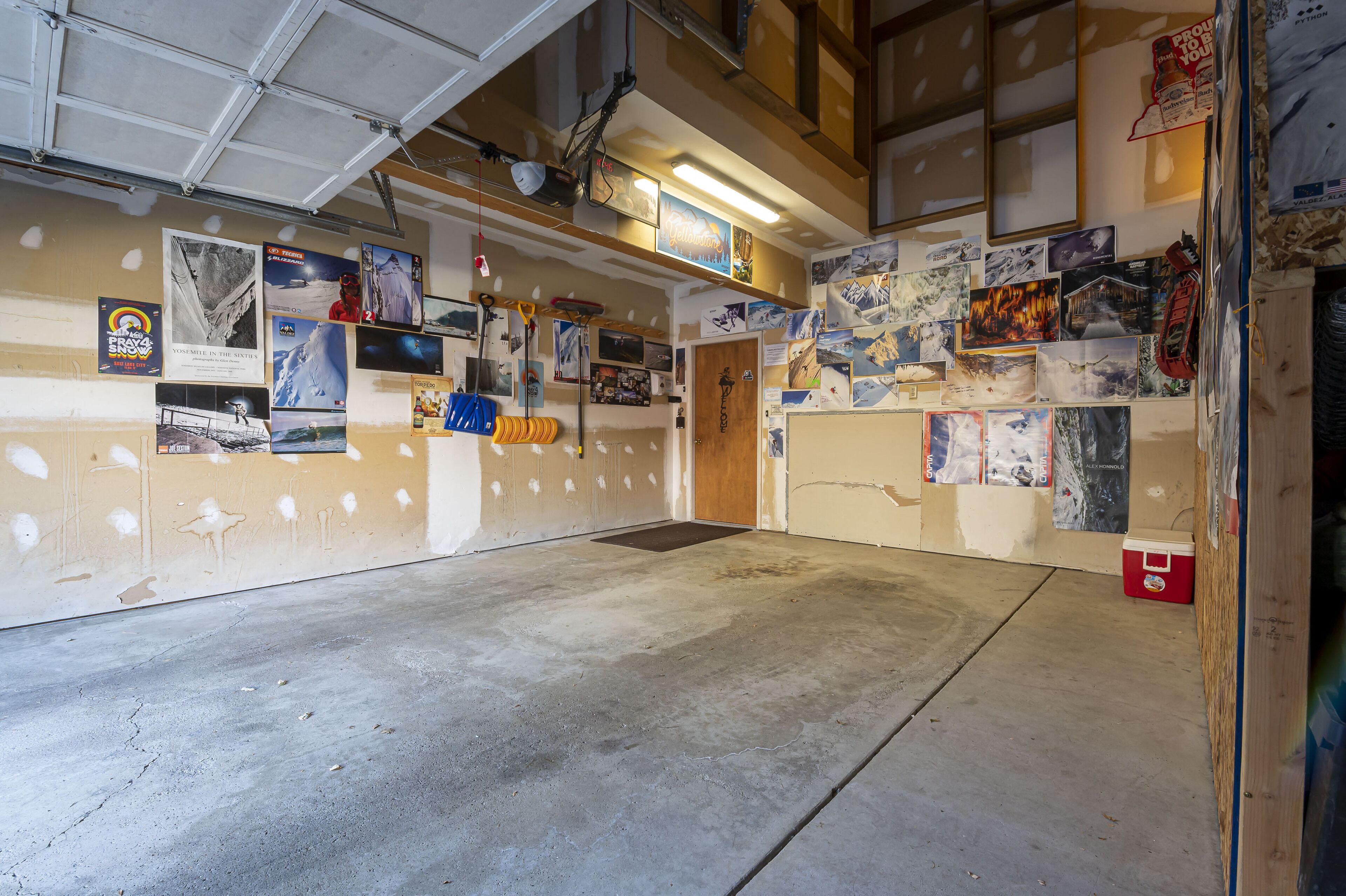 Ett garage med betonggolv, träväggar och diverse affischer och fotografier.