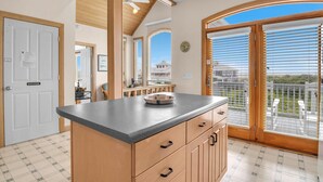 Cucina con un'isola grande, mobili in legno e vista all'esterno.