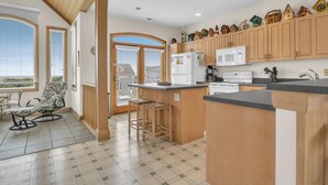 Una cucina con mobili in legno, un'isola centrale e un'area pranzo con una sedia e un tavolo.