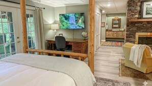 Camera da letto con letto a baldacchino, una scrivania con sedia, televisione, camino in pietra e bagno con lavabo e specchio.