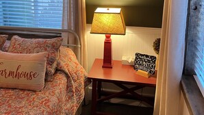 A cozy room with a bed, a lamp, a welcome sign, and a bookshelf.