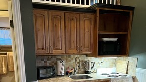 A compact kitchen with wooden cabinets, a built-in microwave, a stove, and a dishwasher.