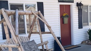 A rustic wooden swing chair with a patterned cushion in front of a building labeled "Country Bunkhouse."