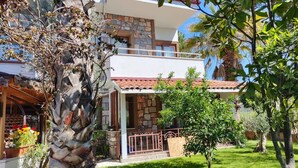 A two-story house with a stone facade, a red-tiled roof, and a small front porch. - Jasmin Apart Hotel (Fethiye)