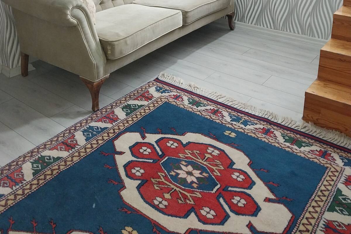 Un salon avec un canapé, un tapis à motifs, un tableau au mur et un escalier.