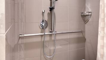 Ein moderner Duschbereich mit Haltegriff, Handbrause und am Wand montierter Armatur.