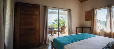 A bedroom with a bed, wooden ceiling, and a view of the outdoors.