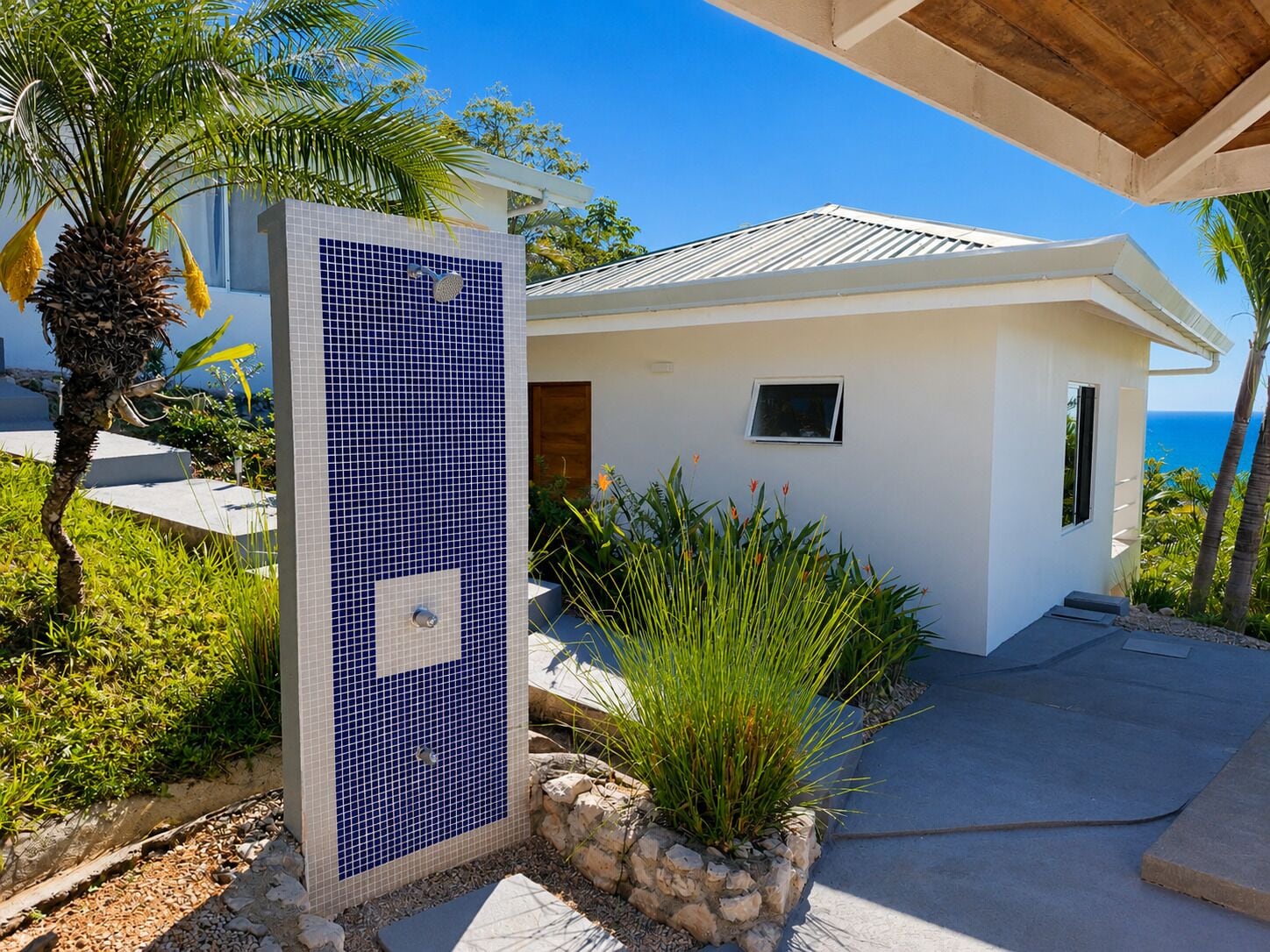 A modern house with a tiled wall, a small window, and a view of the ocean.
