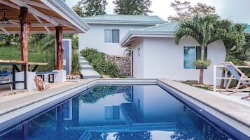 Una piscina al aire libre, sillones reclinables de piscina
