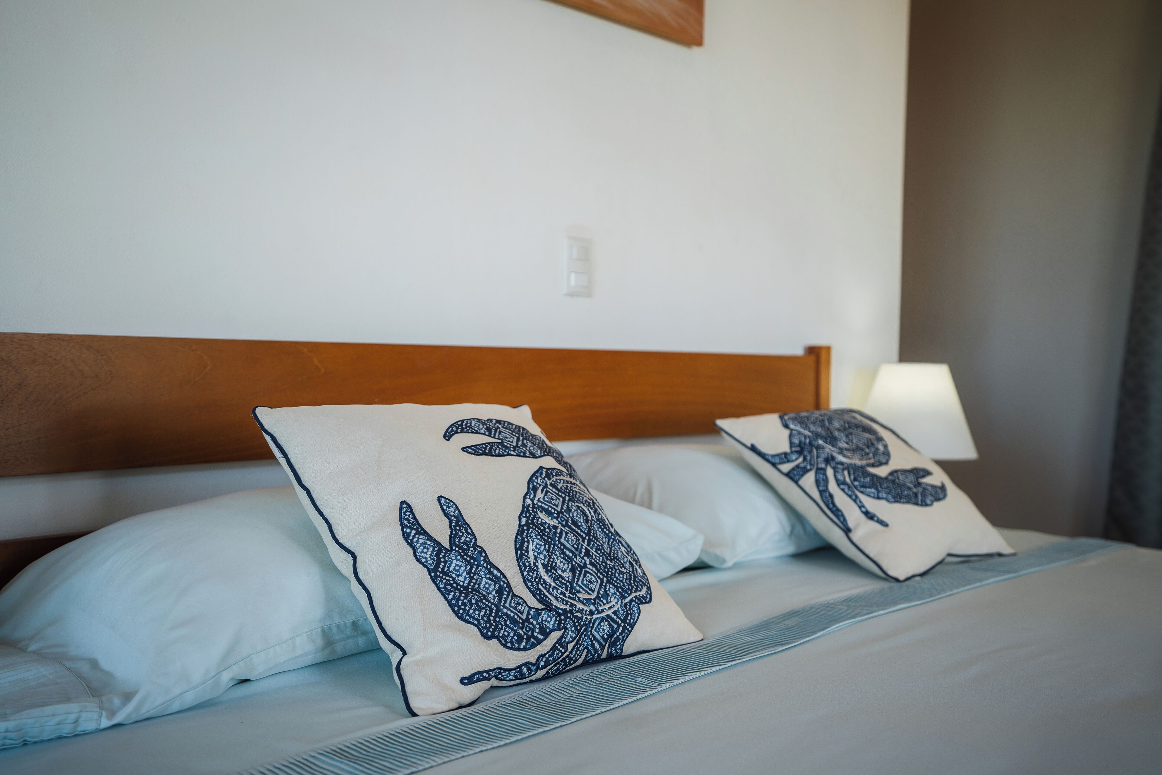 A bed with two pillows featuring a turtle design, a wooden headboard, and a bedside lamp.