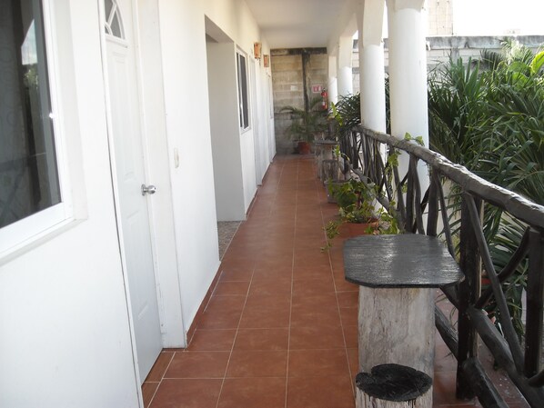 A corridor with white doors, a tiled floor, and a wooden railing with potted plants. - Kukulcan by Emotion (Tulum)