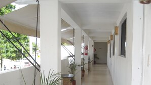 Um corredor com paredes brancas, plantas em vasos e um extintor de incêndio.