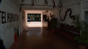 Um corredor com um banco de madeira, decorações penduradas e uma placa que diz "TE KULICAN Emotion".