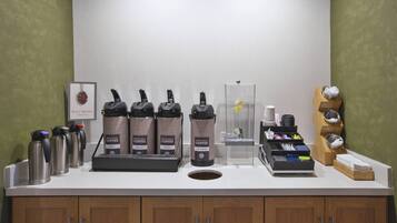 A coffee station with multiple coffee makers, a water dispenser, and a coffee grinder.