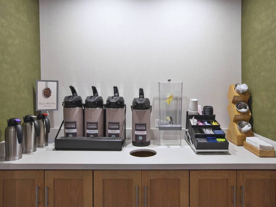 A coffee station with multiple coffee makers, a water dispenser, and a coffee grinder.