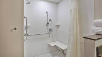 Un baño con paredes de azulejos blancos, una ducha con cabezal de ducha manual, un asidero, un banco y un perchero.