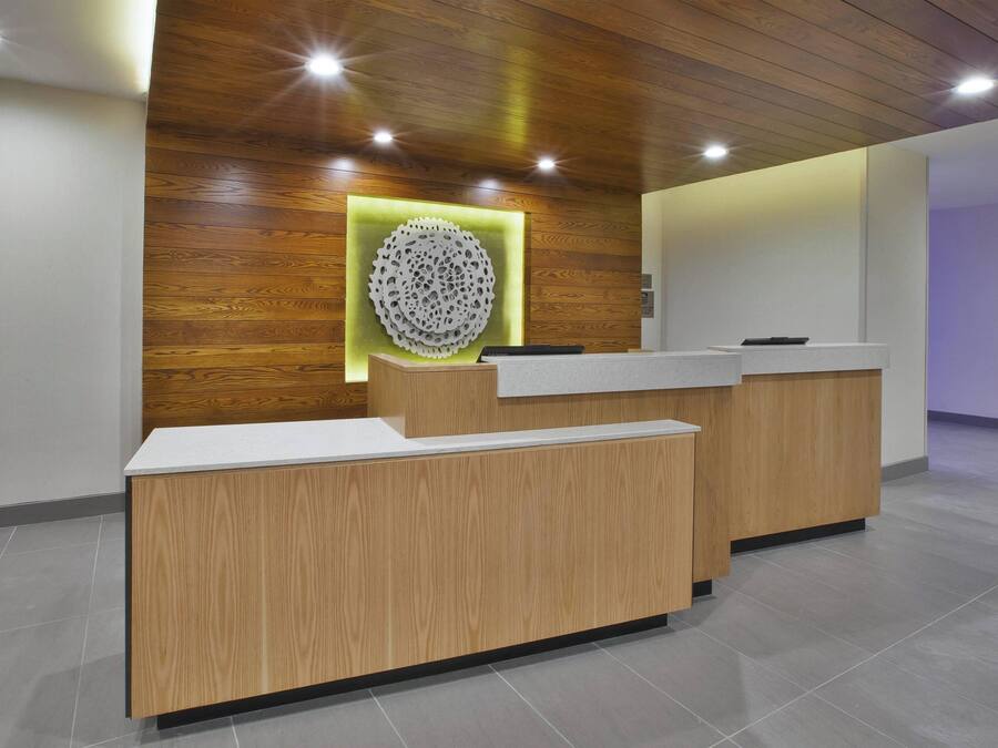 A reception desk with a wooden finish and a modern design, featuring a circular decorative element on the wall behind it.