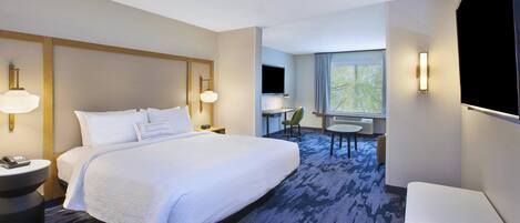 A hotel room with a large bed, bedside tables, a desk, a chair, a TV, and a window with a view.