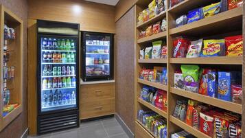 A snack and beverage vending area with multiple shelves stocked with various snacks and drinks.
